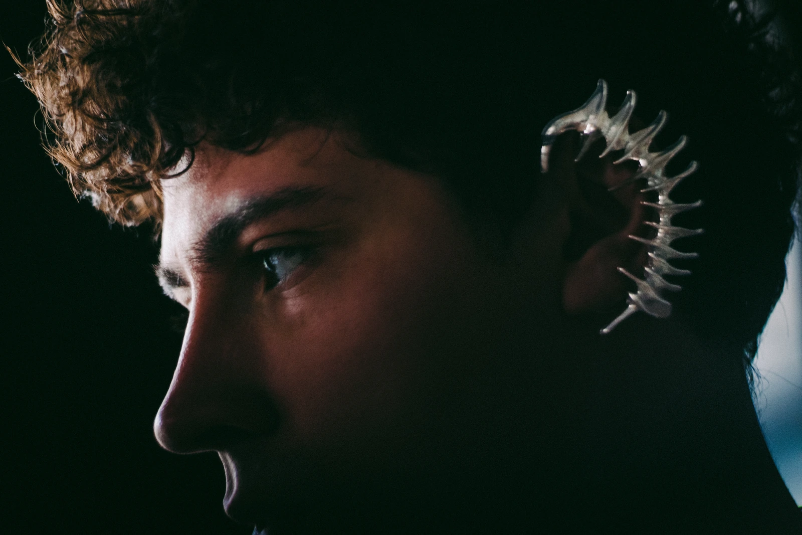 Close portrait of DISTEYO wearing a sculptural silver ear piece